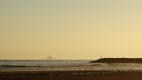 Silhouette-Eines-Einsamen-Fischers,-Der-Bei-Sonnenuntergang-Auf-Einem-Wellenbrecher-Fischt,-Weitschuss