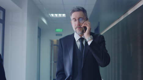 un hombre de negocios hablando por teléfono en el pasillo de la oficina.