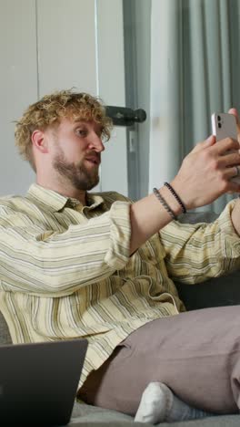 hombre tomando una selfie mientras está en una llamada de video en un sofá