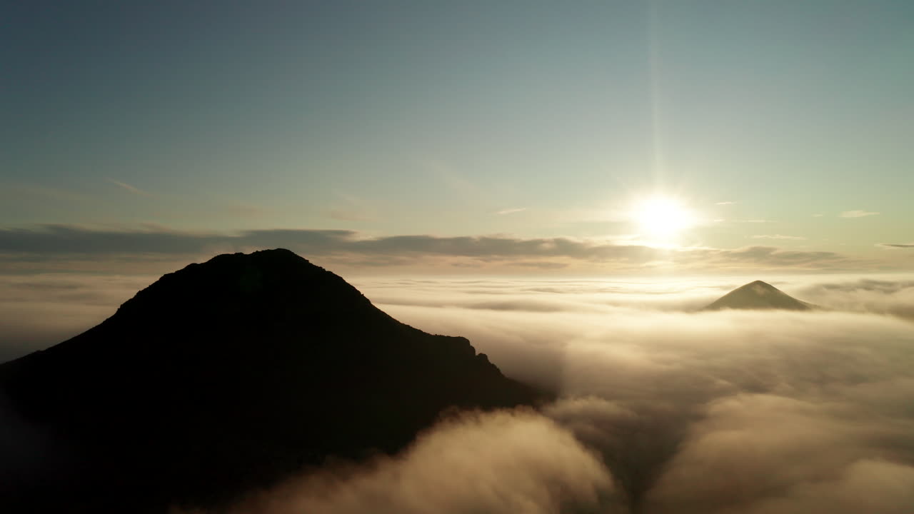 산이 뾰족하고 빛나는 태양이 있는 구름 위의 공중 궤도