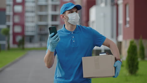 an young mailman courier with a protective mask and gloves is delivering a parcel directly to a customer home with safety. concept of courier home delivery e-commerce shipping virus covid