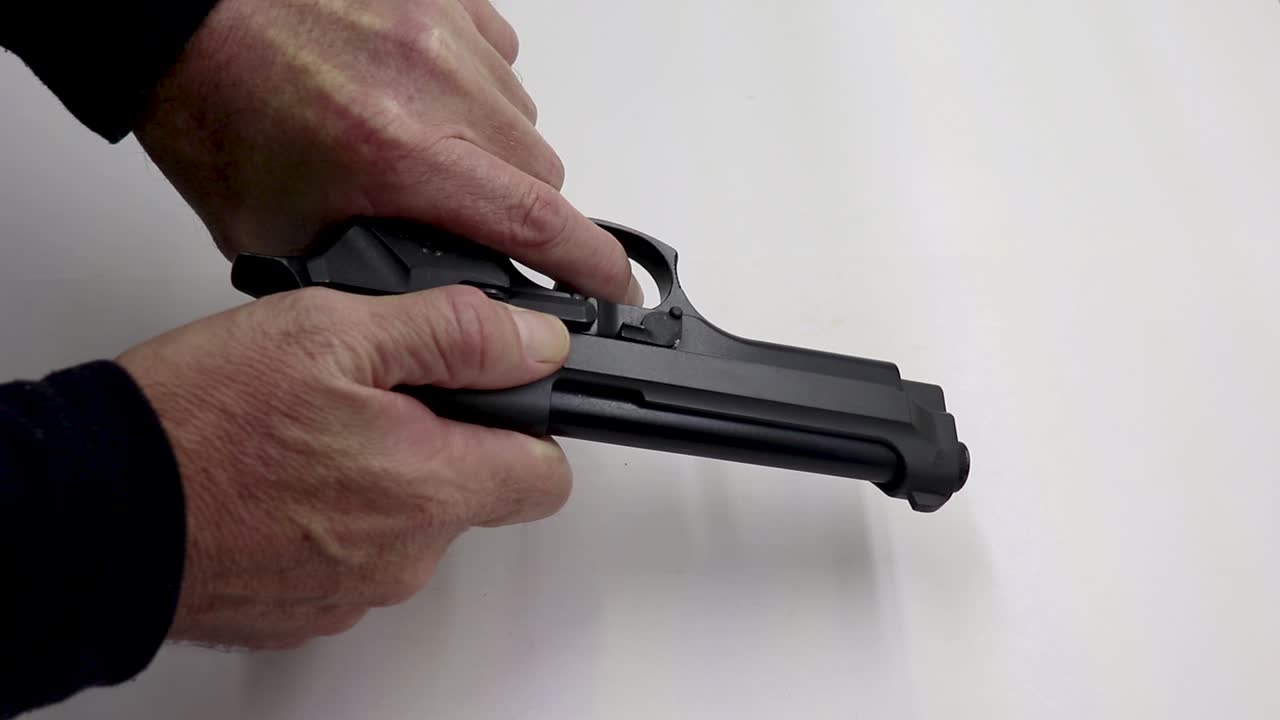 Person pushing a magazine with bullets into a firearm then cocks it