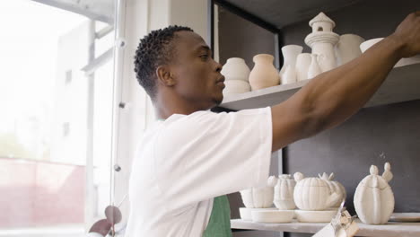 close up of a young american male clerk writing on a clipboard and making an inventory of ceramics in the pottery shop