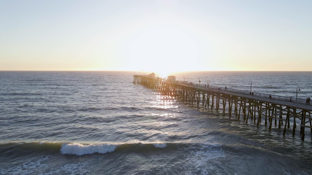 Spettacolare ripresa aerea con drone del molo di San Clemente durante il tramonto, mentre le onde si infrangono sulla spiaggia statale di San Clemente