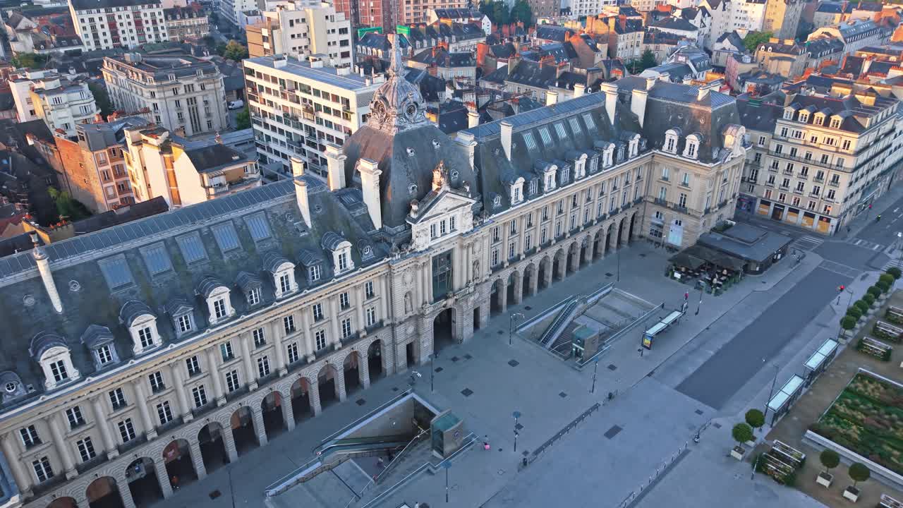 Place de la Republique, square and Palais du Commerce in Rennes, France at sunrise, golden light on historic architecture. Aerial drone forward descending