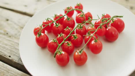 video of fresh cherry tomatoes on white plate over wooden background