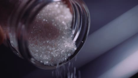 pouring white coarse sugar from a jar - close up shot