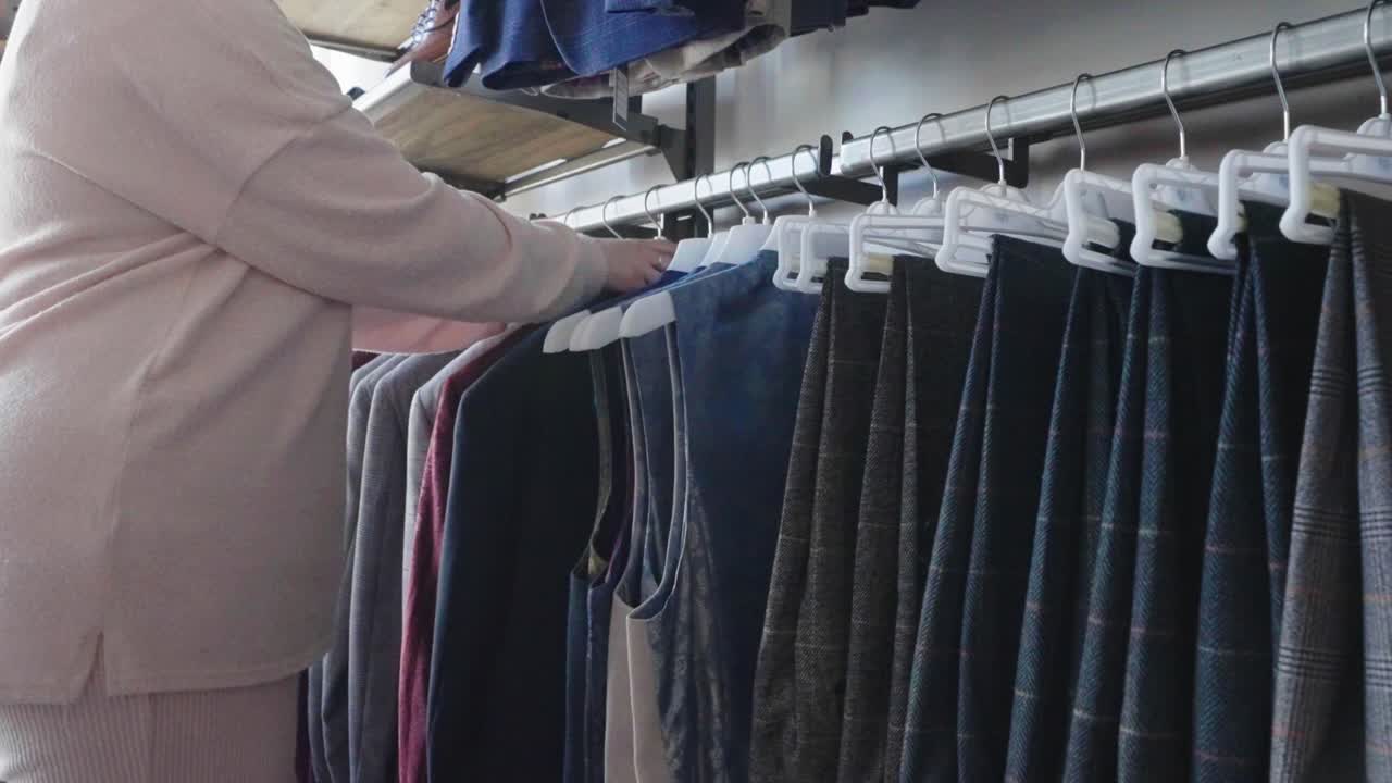 Store assistant sorting display of tartan jackets and waistcoats on hangers
