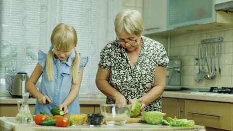 Niña-Divertida-De-6-Años-Ayuda-A-Su-Abuela-A-Preparar-Comidas-En-La-Cocina