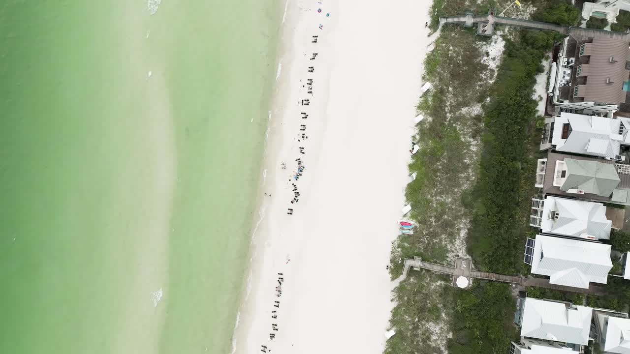 직선 다운 느린 스핀 모션과 파도 움직임과 함께 로즈메리 해변의 전망, 모래, 덤불 및 일부 집에 라운지 의자