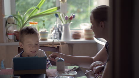 madre jugando con el hijo y el bebé lactante durante el desayuno