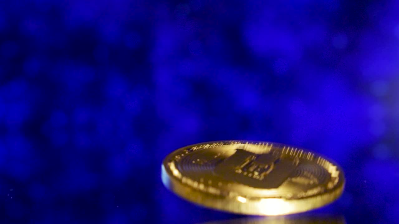 primer plano de dejar caer una moneda de oro en un suelo de espejo con un fondo azul en movimiento futurista