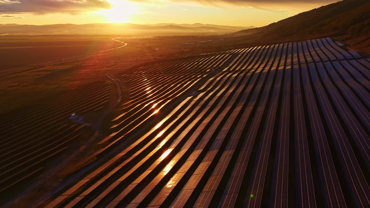 Solpaneler dækker bakkeskråningen, mens solen går ned over et vedvarende energianlæg på landet.