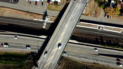 Hiperlapso-De-La-órbita-Aérea-De-Los-Automóviles-Que-Conducen-Por-La-Autopista-1-Y-Una-Carretera-De-Intersección-De-Paso-Subterráneo-Y-Vías-De-Tren-En-Kamloops,-Thompson-Okanagan-En-Un-Entorno-Desértico