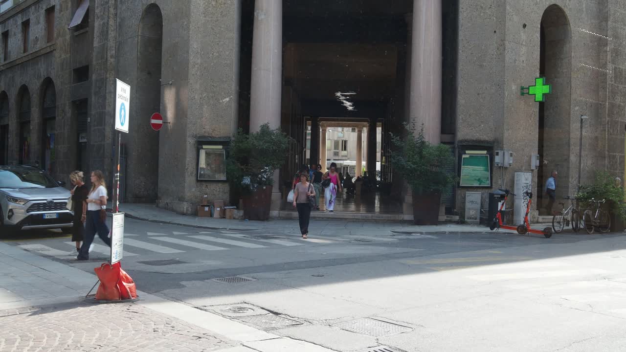 City street scene with people walking, out of XXV Aprile Gallery capturing the motion blur and vibrant urban energy in Cremona Italy