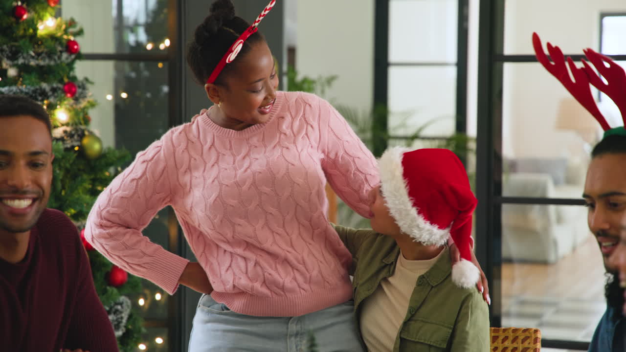 diverse friends laughing and celebrating Christmas together by decorated tree at home