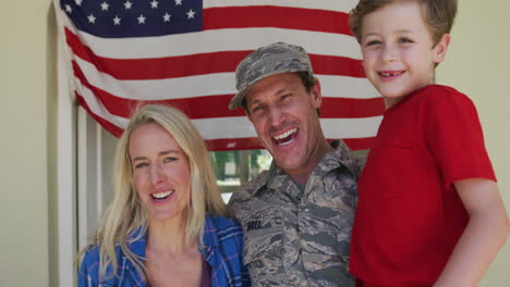 portrait of caucasian male soldier embracing his wife and son over american flag