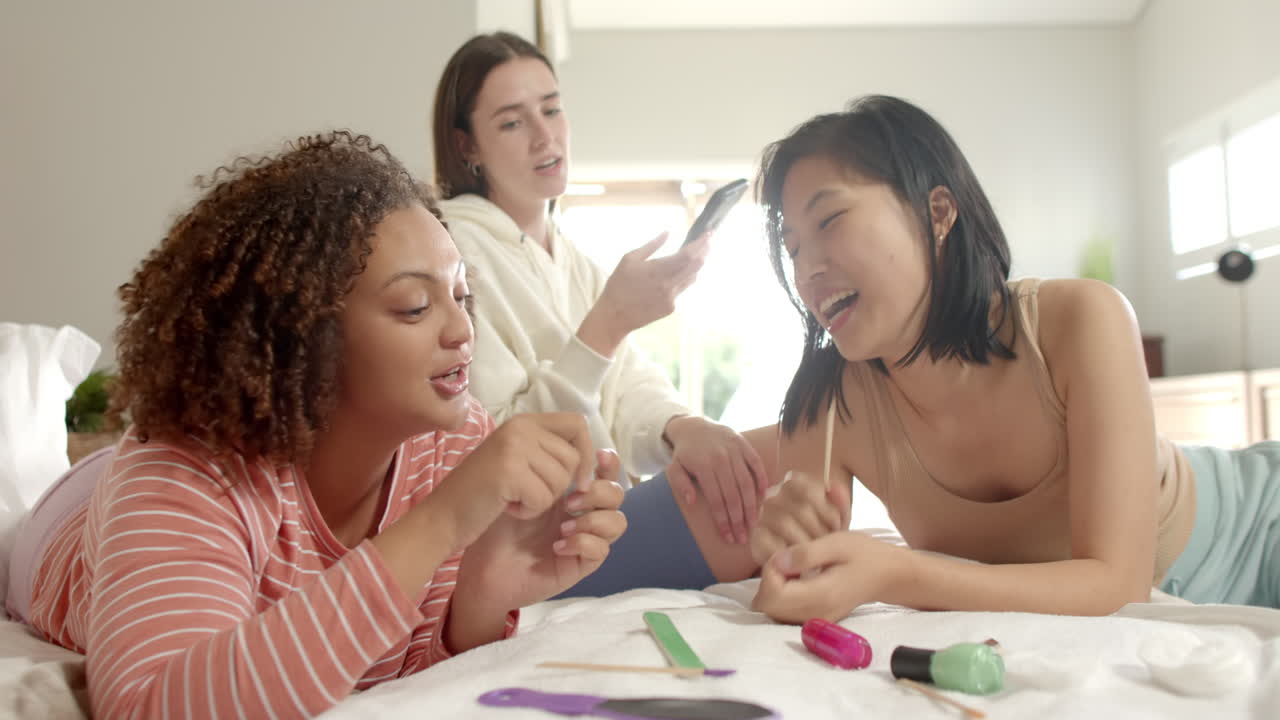 Painting nails and chatting, three women friends enjoying time together at home