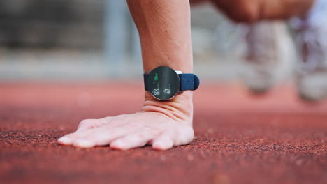 Athletic-man-training-on-red-running-track-with-smartwatch-display-tracking-ECG,-heart-rate-and-training-progress