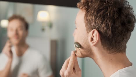 Portrait-of-man-doing-facial-skin-massage-with-jade-roller