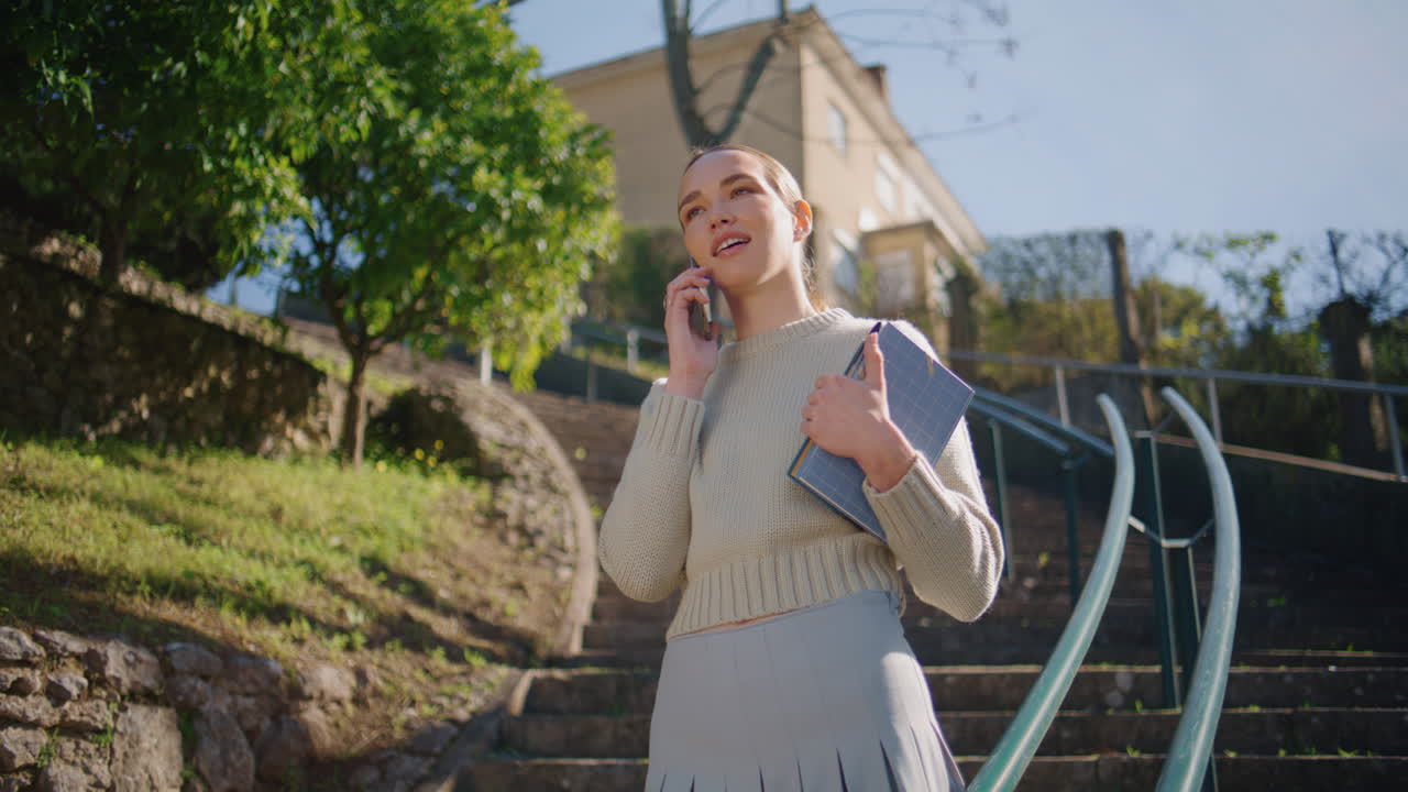 Smiling woman talking mobile phone call sharing good news at sunny park closeup