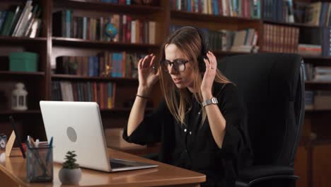 the girl is sitting in a chair, putting on headphones