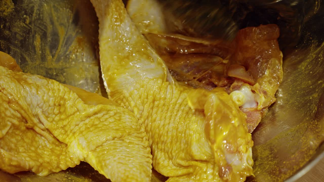 금속 그릇 안에 심황과 소금으로 손으로 양념한 닭 허벅지살