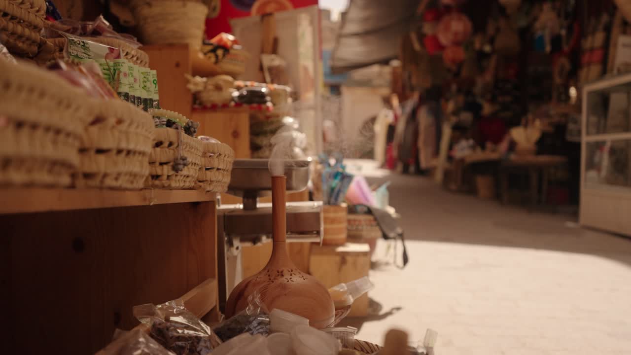 Smoke rises from a traditional incense burner placed outside a Moroccan market stall