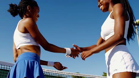 female tennis players shaking hands on court