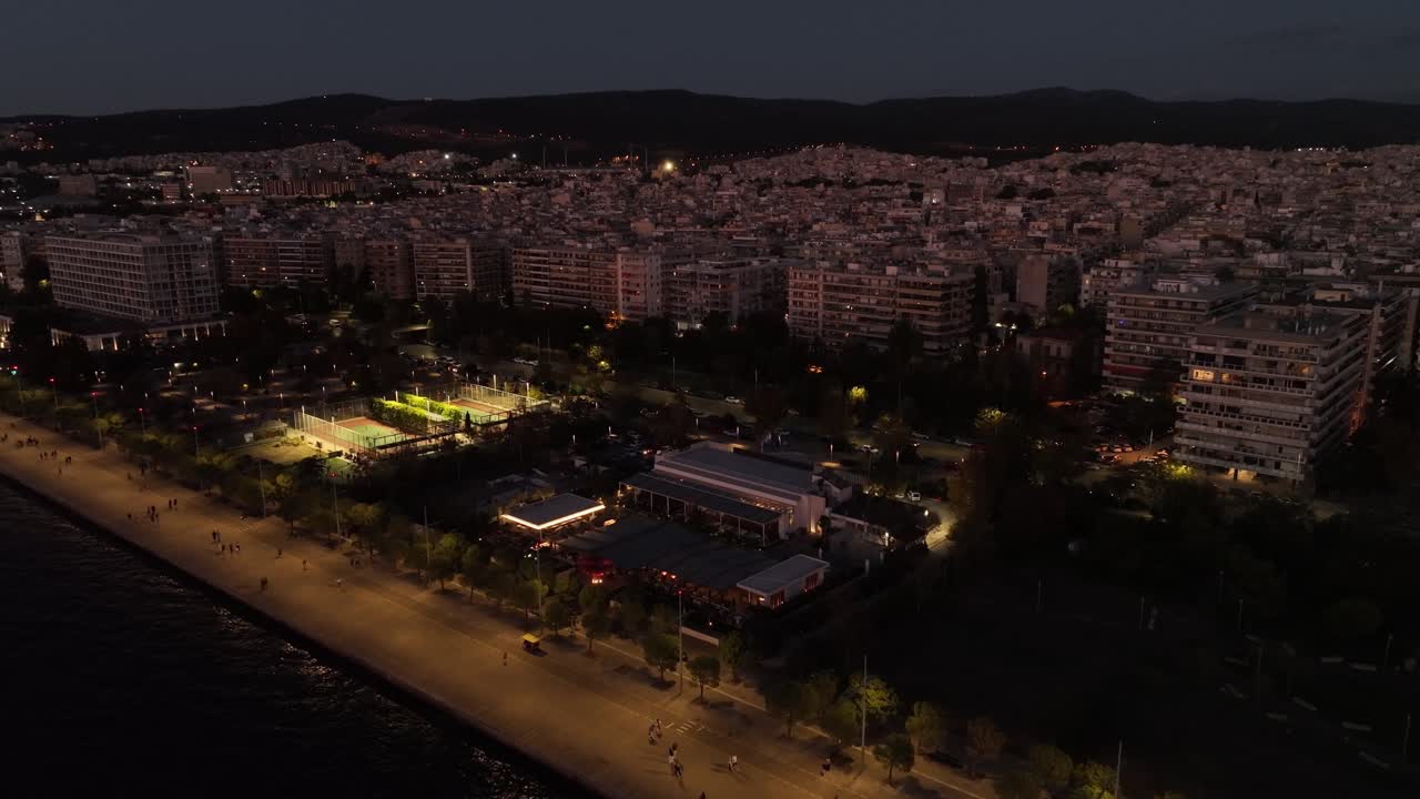 Thessaloniki at night with illuminated streets, coastline, and buildings, aerial view