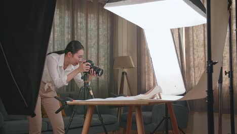 asian female photographer walking into home studio and taking photos of women's shoes