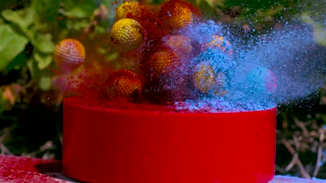 yellow balls with texture covered with blue and red chalk powder being thrown with another ball in slow motion