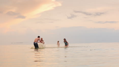 children and adults play in the water laughing splash worm water at each other