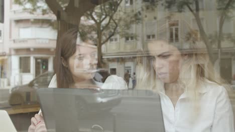 colegas mujeres usando laptop y hablando