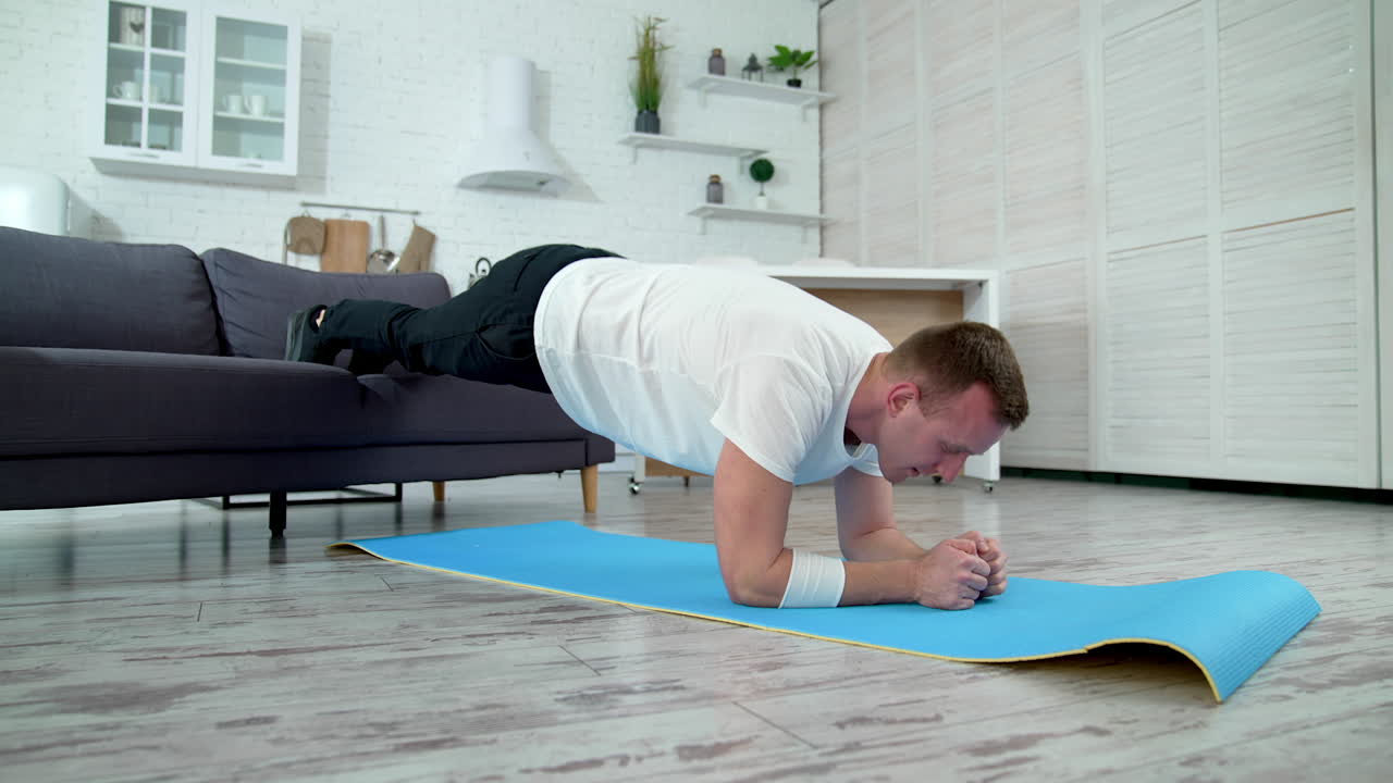 Young man is training at home. Handsome guy exercising hard to maintain body shape during isolation. Sport during quarantine.