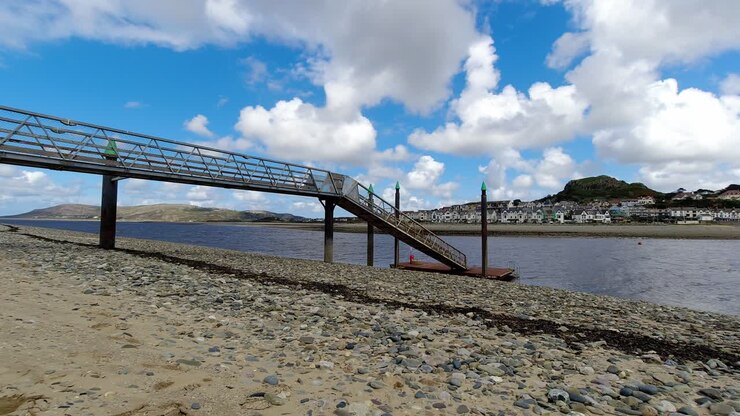 Piattaforma di passerella sopraelevata in un porto con molo galleggiante sulla spiaggia di Llandudno sotto un cielo suggestivo e rilassante