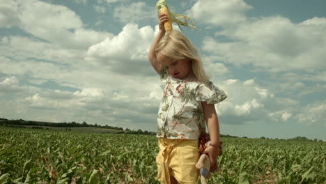 little girl pretends to be maize in the middle of the field.