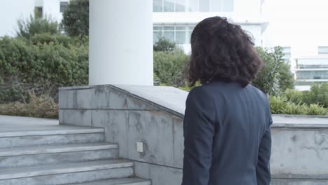 side and back view of a pensive businesswoman in suit walking upstairs outside