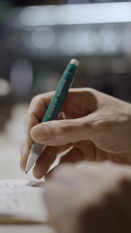 close-up of hand writing with a green mechanical pencil