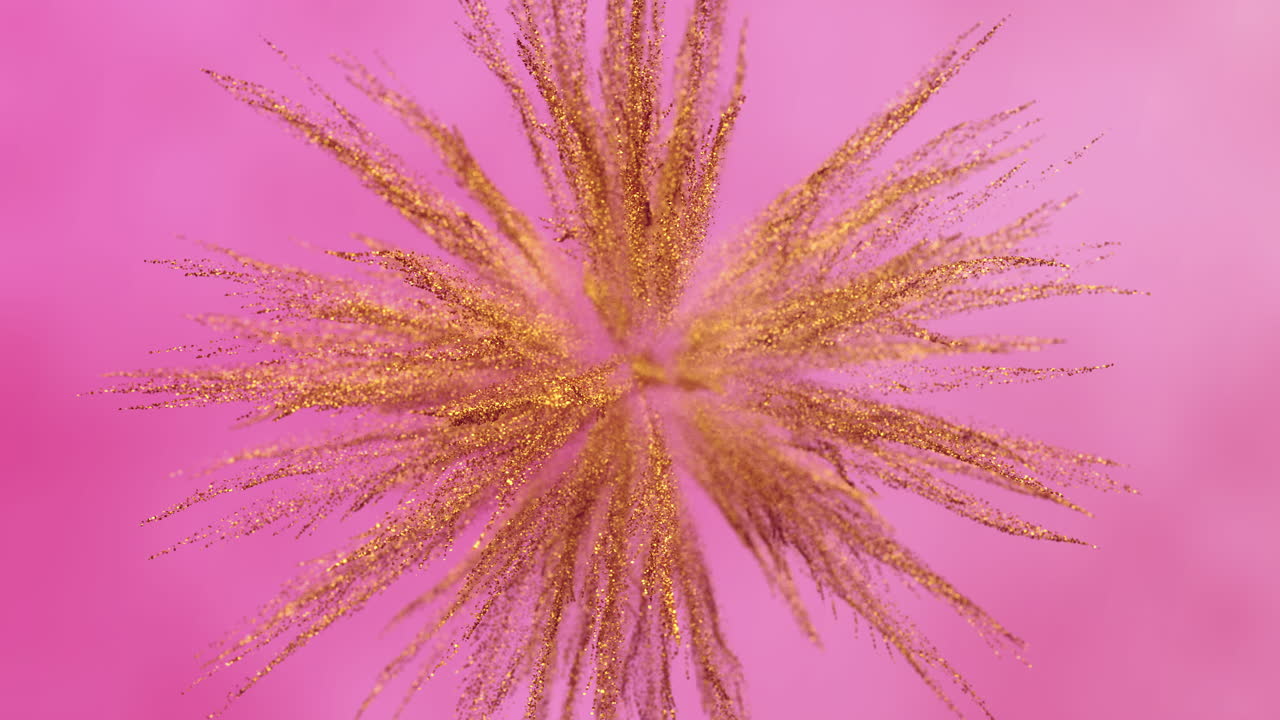 Esplosione di glitter dorati su uno sfondo rosa vivace