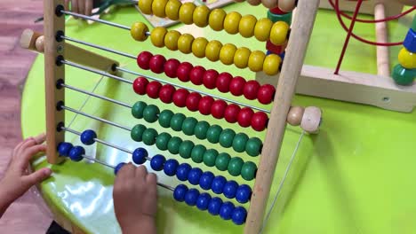 a young child interacts with a colorful abacus, learning to count and sort. perfect for educational content, e-learning visuals, or preschool promos. captured in crisp 4k resolution.