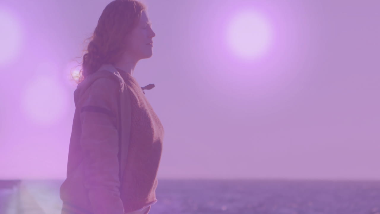 Standing by ocean, woman with purple light animation in background