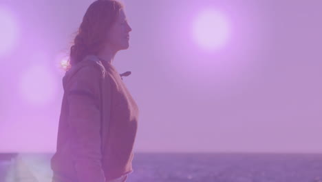 standing by ocean, woman with purple light animation in background