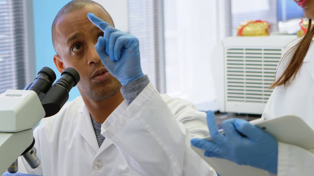 científico interactuando con su colega mientras usa el microscopio 4k