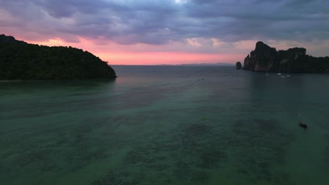 Fantastischer-Luftbildflug-über-Eine-Tropische-Insel-Bei-Sonnenuntergang-Und-Bewölktem-Himmel-Mit-Booten,-Die-Auf-Einem-Türkisfarbenen-Meer-Segeln