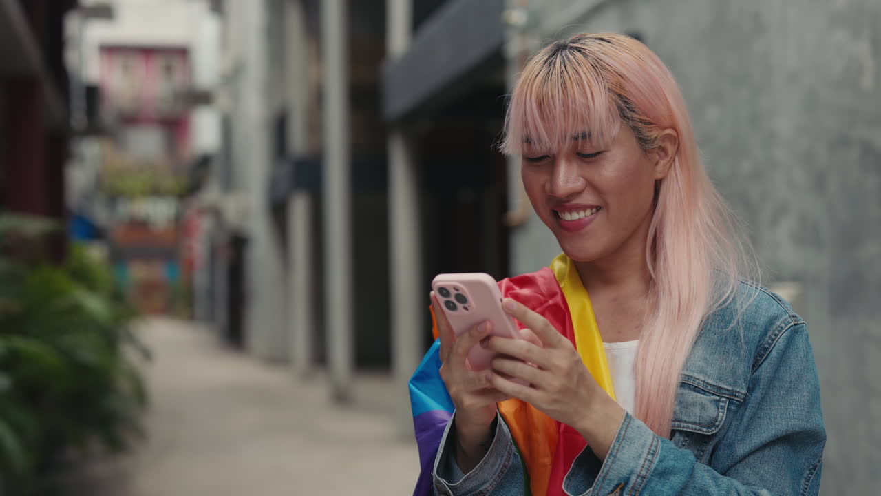 Woman using a phone, wearing pride flag