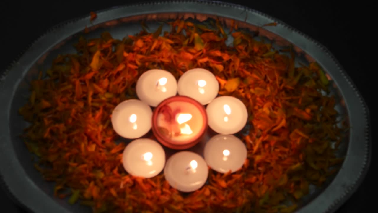Tilt down to Diyas or lamps in a silver plate with petals lit up for Diwali 'Festival of light', important ancient Hindu festival celebrated signifying victory of light over darkness