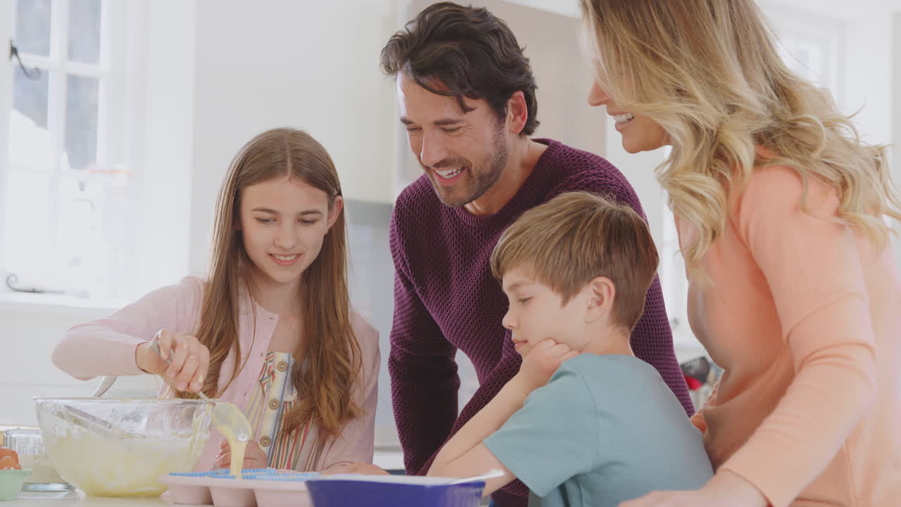 집에서 주방에서 두 아이와 함께 가족이 함께 재미있는 베이킹 케이크를 즐기고 있습니다.