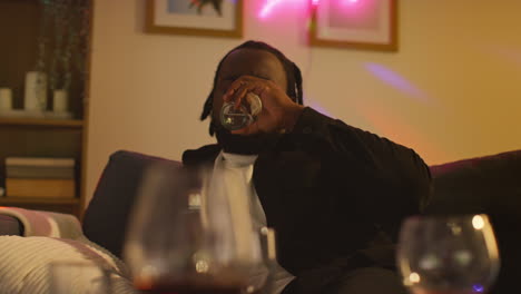 man sitting on sofa after drinking alcohol at house party drinking glass of water for hangover 4