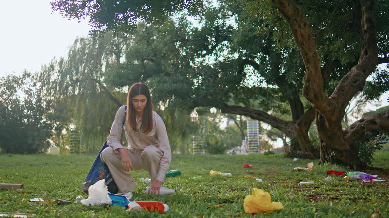 niña caminando recogiendo basura en el parque verde de la noche. conservacionista femenina